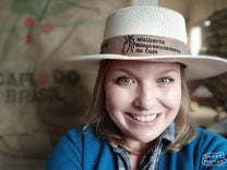 Andréia Moreira poses for a photo wearing her “Mulheres Empreendedoras do Cafe” hat, a local women’s coffee association that includes all parts of the chain.