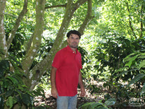Anibal Erazo poses for a photo beneath the shade trees at his farm in El Cedral, Honduras.